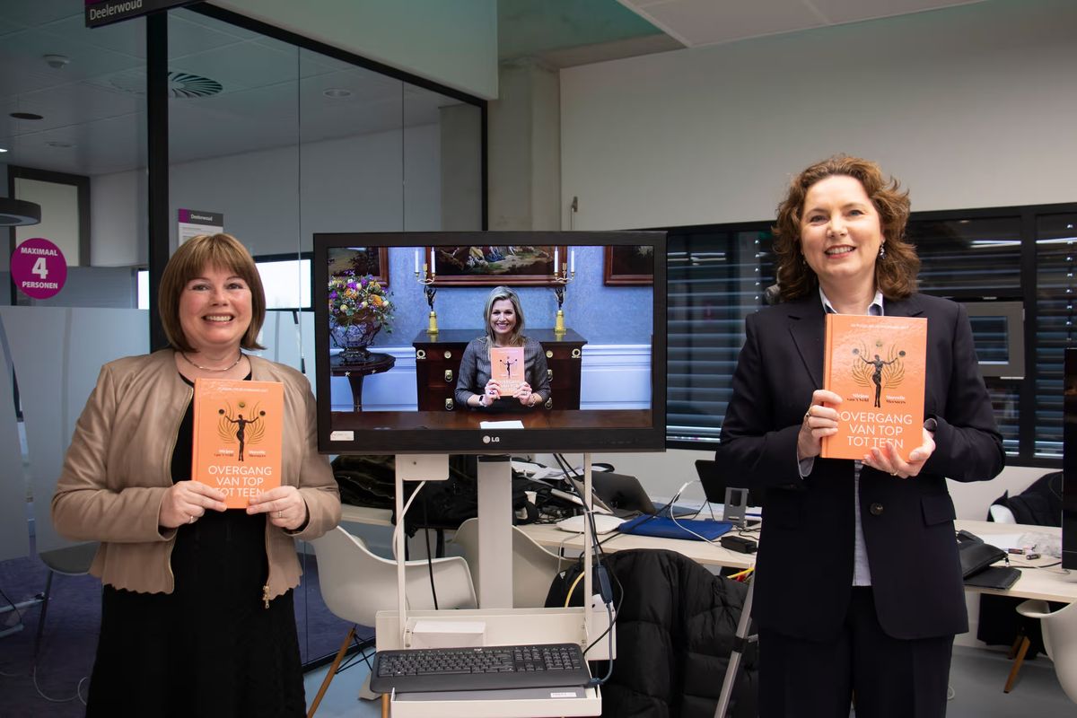 Marcelle Meesters en Mirjam van 't Veld met hun boek Overgang van top tot teen, op het scherm koningin Máxima met het eerste exemplaar
